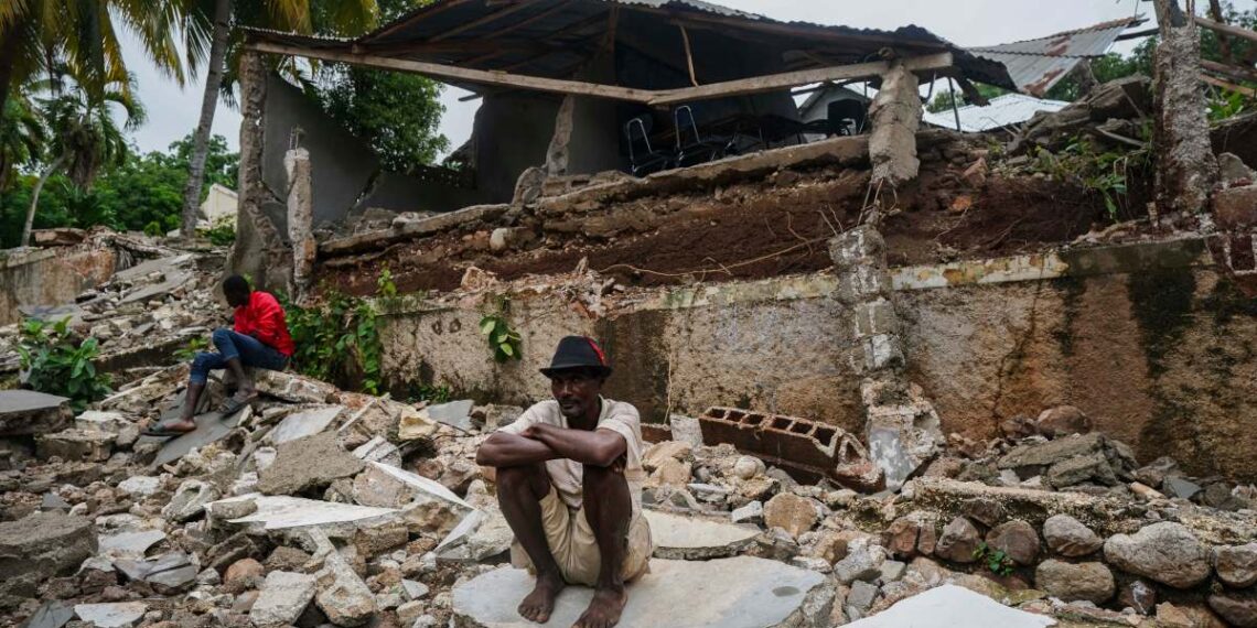 A man crouches on the rubble of the hospital destroyed by the earthquake in Fleurant, Haiti, Tuesday, Aug. 17, 2021, three days after the 7.2-magnitude quake hit the Caribbean nation. (AP Photo/Fernando Llano)