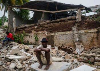 A man crouches on the rubble of the hospital destroyed by the earthquake in Fleurant, Haiti, Tuesday, Aug. 17, 2021, three days after the 7.2-magnitude quake hit the Caribbean nation. (AP Photo/Fernando Llano)