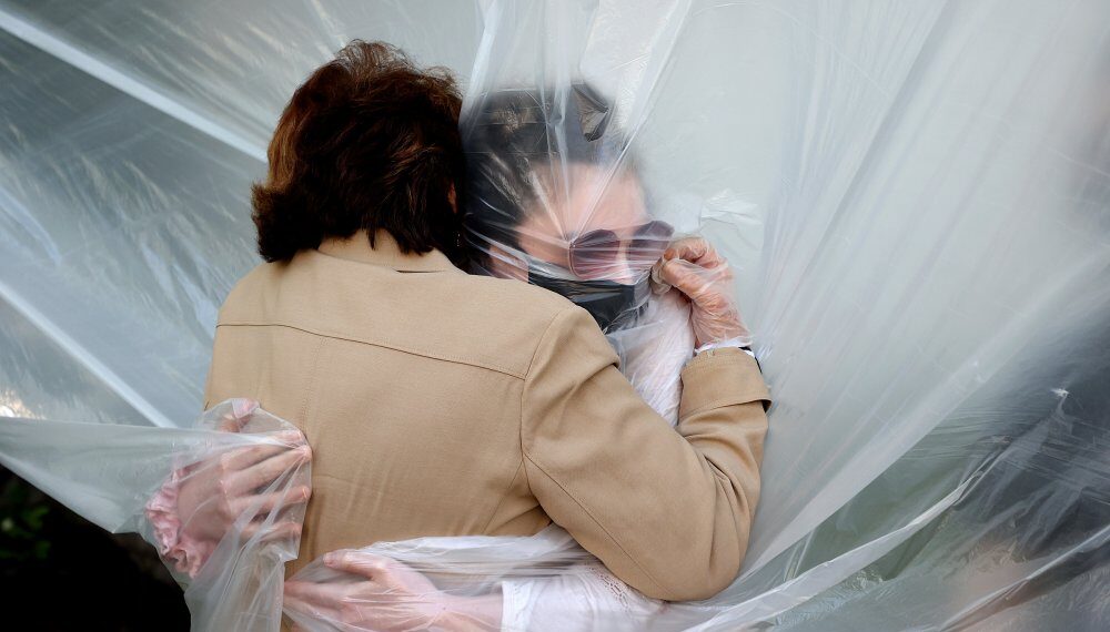 WANTAGH, NEW YORK - MAY 24:   Olivia Grant (R) hugs her grandmother, Mary Grace Sileo through a plastic drop cloth hung up on a homemade clothes line during Memorial Day Weekend on May 24, 2020 in Wantagh, New York.  It is the first time they have had contact of any kind since the coronavirus COVID-19 pandemic lockdown started in late February.  (Photo by Al Bello/Getty Images)