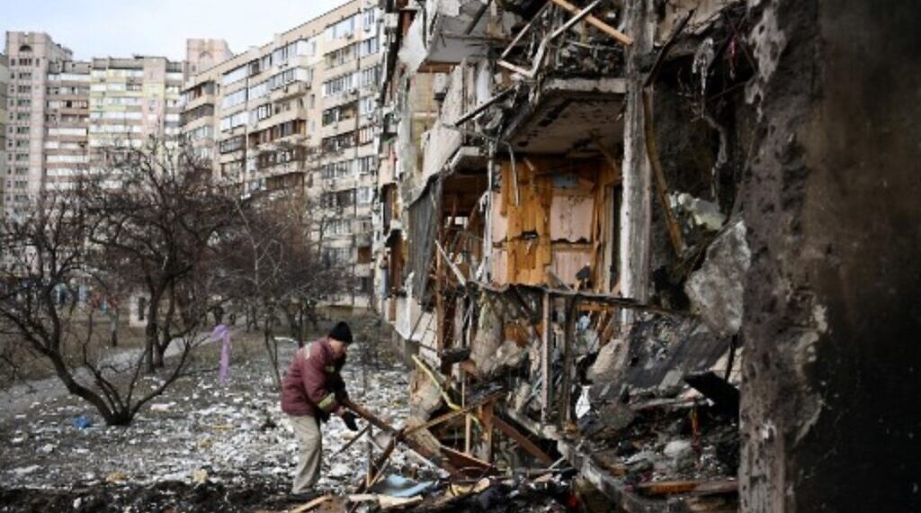 A man clears debris at a damaged residential building at Koshytsa Street, a suburb of the Ukrainian capital Kyiv, where a military shell allegedly hit, on February 25, 2022. - Russian forces reached the outskirts of Kyiv on Friday as Ukrainian President Volodymyr Zelensky said the invading troops were targeting civilians and explosions could be heard in the besieged capital. Pre-dawn blasts in Kyiv set off a second day of violence after Russian President Vladimir Putin defied Western warnings to unleash a full-scale ground invasion and air assault on Thursday that quickly claimed dozens of lives and displaced at least 100,000 people. (Photo by Daniel LEAL / AFP)