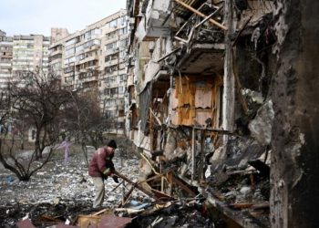 A man clears debris at a damaged residential building at Koshytsa Street, a suburb of the Ukrainian capital Kyiv, where a military shell allegedly hit, on February 25, 2022. - Russian forces reached the outskirts of Kyiv on Friday as Ukrainian President Volodymyr Zelensky said the invading troops were targeting civilians and explosions could be heard in the besieged capital. Pre-dawn blasts in Kyiv set off a second day of violence after Russian President Vladimir Putin defied Western warnings to unleash a full-scale ground invasion and air assault on Thursday that quickly claimed dozens of lives and displaced at least 100,000 people. (Photo by Daniel LEAL / AFP)