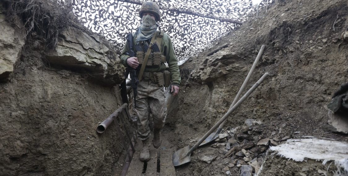 Ukrainian soldiers walks under a camouflage net in a trench on the line of separation from pro-Russian rebels near Debaltsevo, Donetsk region, Ukraine, Ukraine Friday, Dec 3, 2021. In this Friday, the Ukrainian defense minister warned that Russia could invade his country next month. Russia-West tensions escalated recently with Ukraine and its Western backers becoming increasingly concerned that a Russian troop buildup near the Ukrainian border could signal Moscow's intention to invade. (AP Photo/Andriy Dubchak)