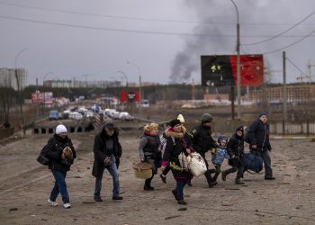 A Ukrainian police officer helps people as artillery echoes nearby while fleeing Irpin in the outskirts of Kyiv, Ukraine, Monday, March 7, 2022. Russia announced yet another cease-fire and a handful of humanitarian corridors to allow civilians to flee Ukraine. Previous such measures have fallen apart and Moscow’s armed forces continued to pummel some Ukrainian cities with rockets Monday. (AP Photo/Emilio Morenatti)