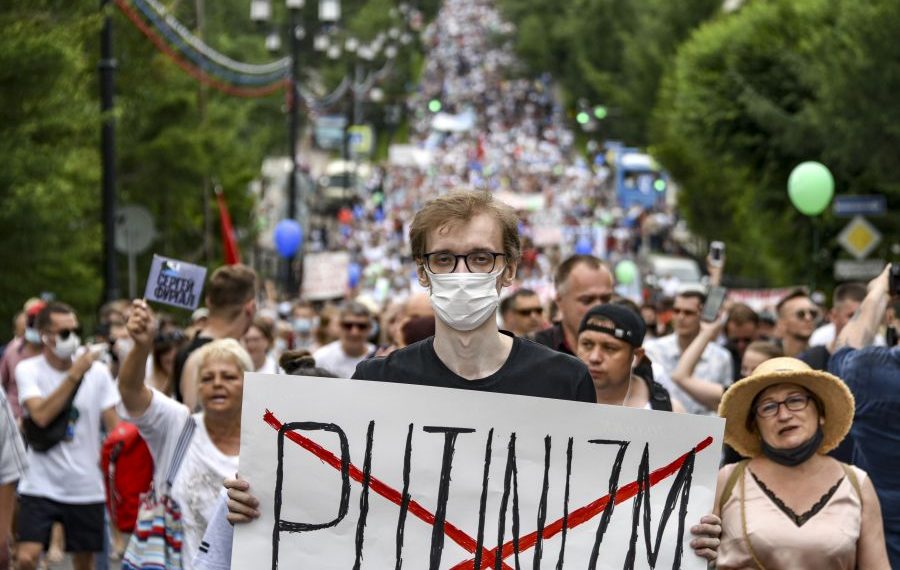 A man holds poster reading "Putinizm " during an unsanctioned protest in support of Sergei Furgal, the governor of the Khabarovsk region, who was interrogated and ordered held in jail for two months, in Khabarovsk, 6100 kilometers (3800 miles) east of Moscow, Russia, Saturday, July 25, 2020. Some thousands marched across Khabarovsk to protest the arrest of the region's governor on murder charges, continuing a wave of protests that has lasted for two weeks. (AP Photo/Igor Volkov)