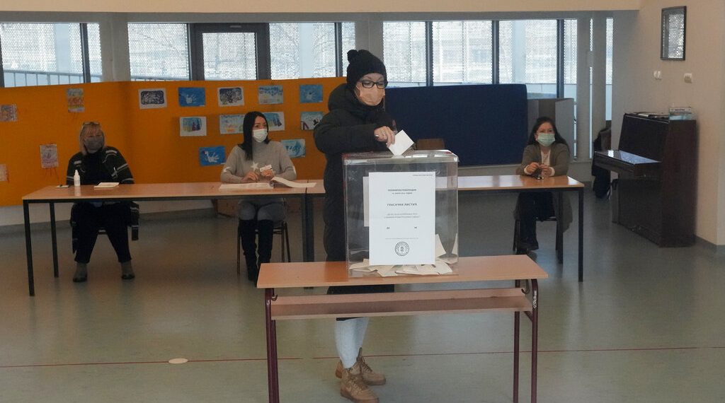 In this photo photographed through a window, a woman casts her ballot for a referendum on constitutional changes, in Belgrade, Serbia, Sunday, Jan. 16, 2022. The government has said the amendments are designed to boost independence of the judiciary and are part of reform needed for Serbia's European Union membership bid. (AP Photo/Darko Vojinovic)