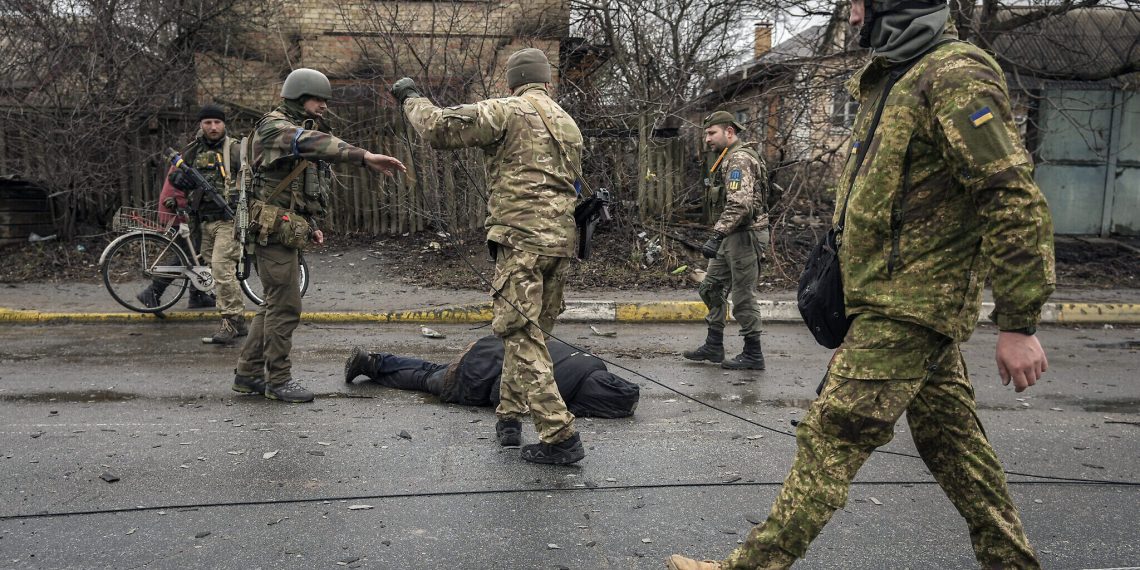 Ukrainian servicemen attach a cable to the body of a civilian while checking for booby traps in the formerly Russian-occupied Kyiv suburb of Bucha, Ukraine, Saturday, April 2, 2022. As Russian forces pull back from Ukraine's capital region, retreating troops are creating a "catastrophic" situation for civilians by leaving mines around homes, abandoned equipment and "even the bodies of those killed," President Volodymyr Zelenskyy warned Saturday.(AP Photo/Vadim Ghirda)