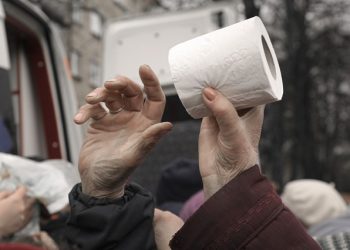 A toilet paper roll changes hands as people wait for medicine and sanitary supplies handouts after a convoy of military and aid vehicles arrived in the formerly Russian-occupied Kyiv suburb of Bucha, Ukraine, Saturday, April 2, 2022. As Russian forces pull back from Ukraine's capital region, retreating troops are creating a "catastrophic" situation for civilians by leaving mines around homes, abandoned equipment and "even the bodies of those killed," President Volodymyr Zelenskyy warned Saturday.(AP Photo/Vadim Ghirda)