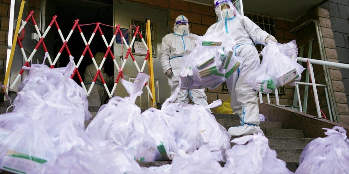 Workers in protective suits prepare to enter a building under lockdown to distribute to residents antigen testing kits for the coronavirus disease (COVID-19), at a residential compound in Beijing's Chaoyang district, China November 21, 2022. China Daily via REUTERS  ATTENTION EDITORS - THIS IMAGE WAS PROVIDED BY A THIRD PARTY. CHINA OUT.