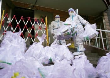 Workers in protective suits prepare to enter a building under lockdown to distribute to residents antigen testing kits for the coronavirus disease (COVID-19), at a residential compound in Beijing's Chaoyang district, China November 21, 2022. China Daily via REUTERS  ATTENTION EDITORS - THIS IMAGE WAS PROVIDED BY A THIRD PARTY. CHINA OUT.