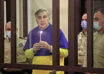 FILE PHOTO: Georgian former President Mikheil Saakashvili, who was convicted in absentia of abuse of power during his presidency and arrested upon his return from exile, holds a candle while praying for Ukraine in a defendant's dock during a court hearing in Tbilisi, Georgia, March 17, 2022. REUTERS/Irakli Gedenidze/File Photo