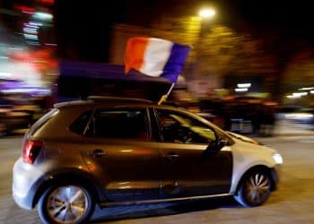 Soccer Football - FIFA World Cup Qatar 2022 - Fans gather in Paris for France v Morocco - Paris, France - December 14, 2022 France fans wave a flag out of a car window as they celebrate on the Champs-Elysees after the match REUTERS/Gonzalo Fuentes     TPX IMAGES OF THE DAY