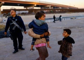 A Venezuelan woman stands with her children as a policeman stands guard near the United States and Mexico border, in Ciudad Juarez, Mexico January 8. 2023. REUTERS/Jose Luis Gonzalez