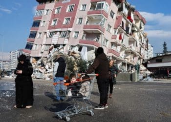 Children sit in a shopping cart near a collapsed building following an earthquake in Hatay, Turkey, February 7, 2023. REUTERS/Umit Bektas     TPX IMAGES OF THE DAY