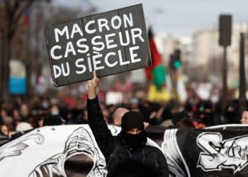 A masked protester holds a placard which reads "Macron, vandal of the century" during a demonstration against French government's pension reform plan in Paris as part of the fifth day of national strike and protests in France, February 16, 2023.  REUTERS/Benoit Tessier