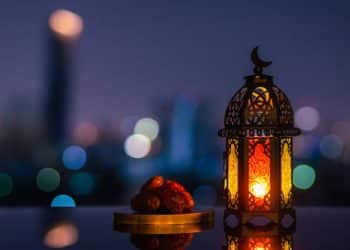 Lantern that have moon symbol on top and small plate of dates fruit with night sky and city bokeh light background for the Muslim feast of the holy month of Ramadan Kareem.